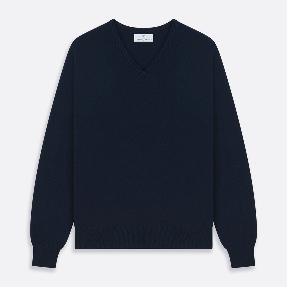 The Turnbull & Asser Navy V-Neck Cashmere Jumper, featuring long sleeves and ribbed cuffs and hem, is laid flat on a white background, showcasing its simple and classic design.