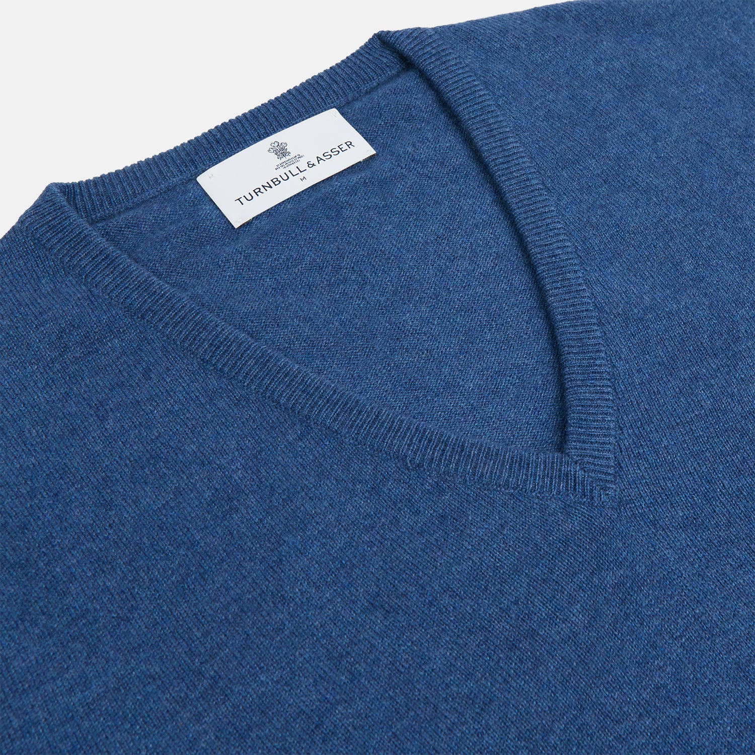 View 2 of product The Turnbull & Asser Blue V-Neck Cashmere Jumper, crafted from soft Scottish cashmere with ribbed cuffs, hem, and neckline, is shown laid flat on a white background for a refined smart-casual appeal.