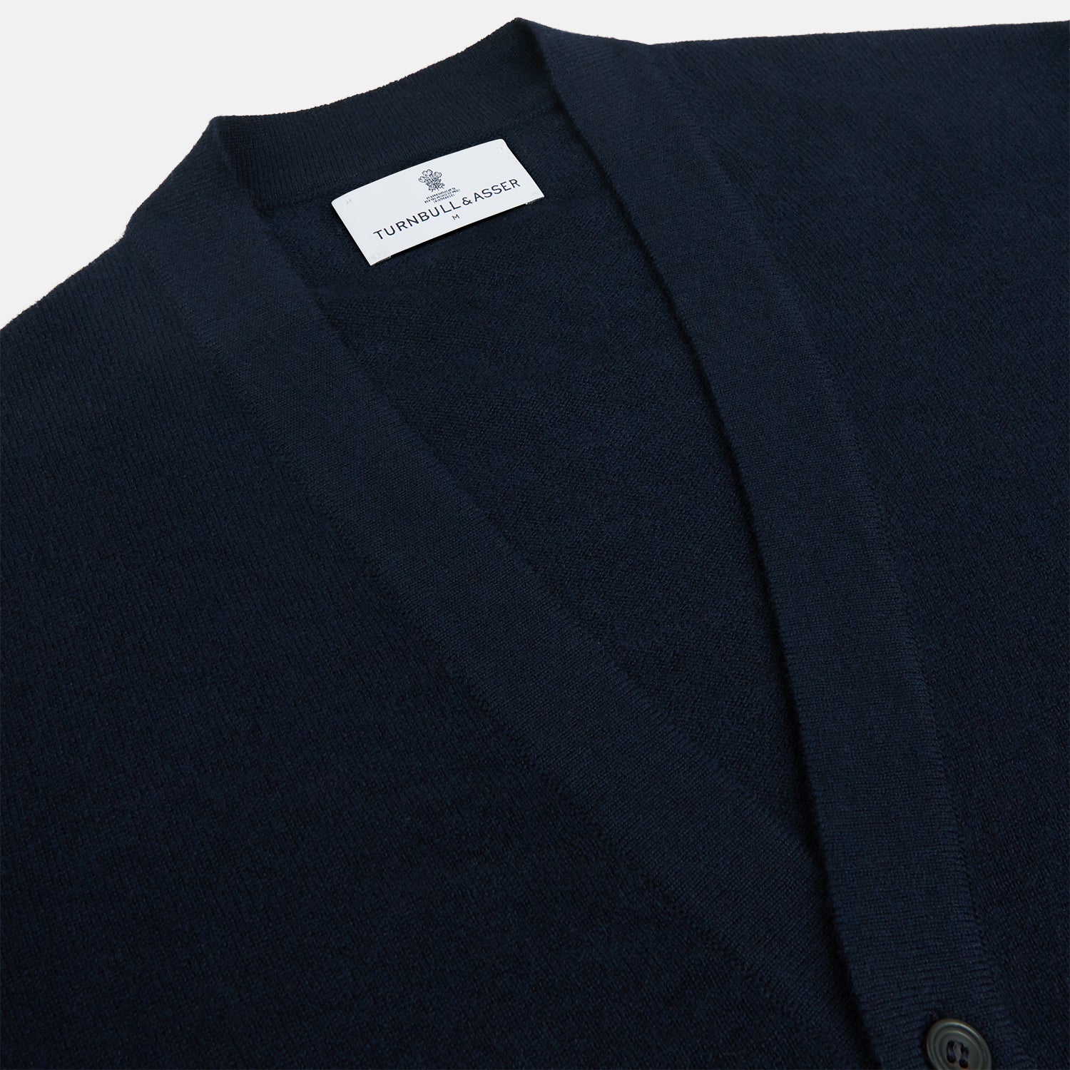 View 2 of product The Navy Cashmere Cardigan by Turnbull & Asser features long sleeves, a V-neckline, button-down front, two front pockets, and ribbed trims, crafted from 21GG cashmere in navy blue and shown laid flat on a white background.