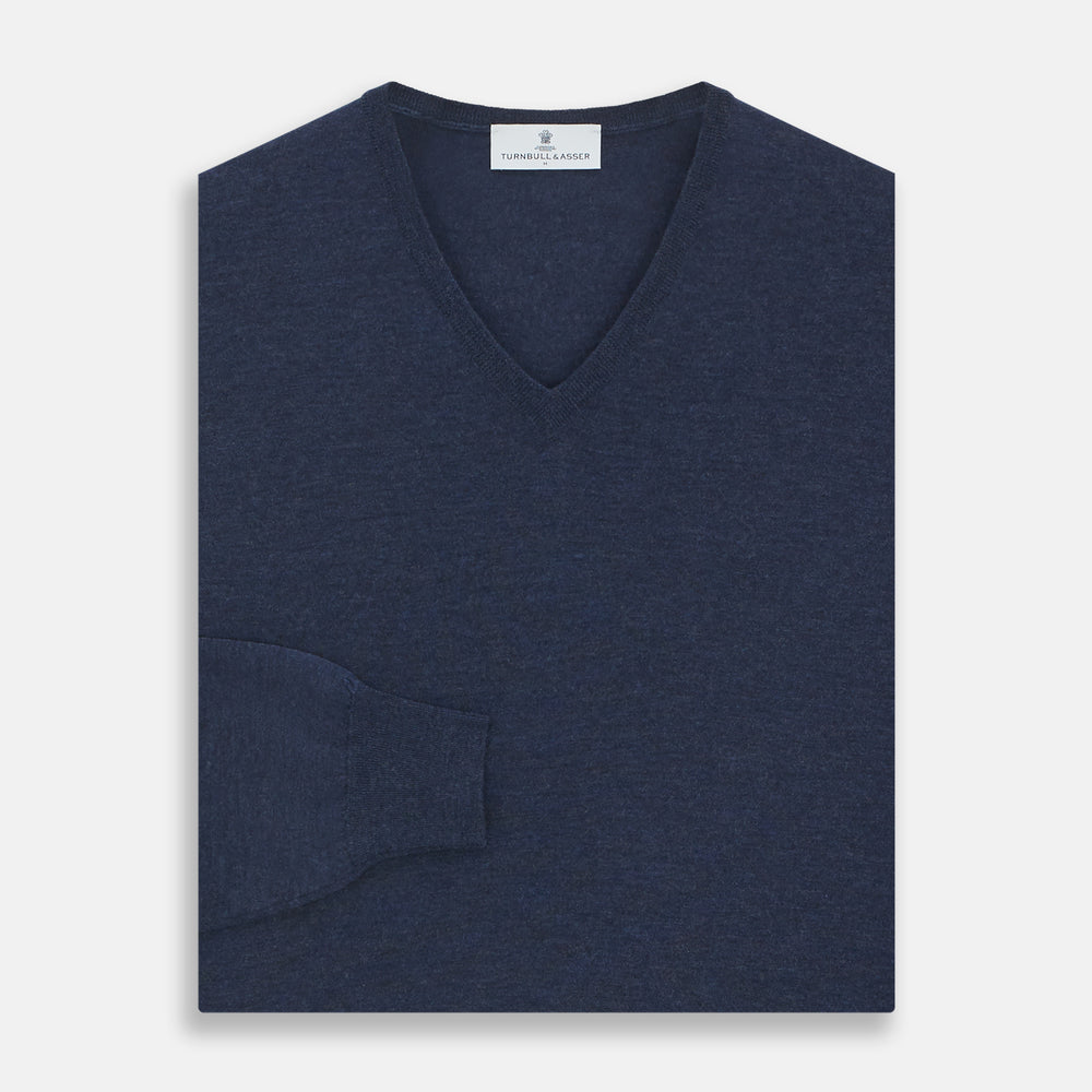The Blue V-Neck Merino Wool Jumper by Turnbull & Asser features long sleeves, ribbed cuffs, and a ribbed hem—a timeless essential for any gentleman's wardrobe, shown laid flat on a white background.