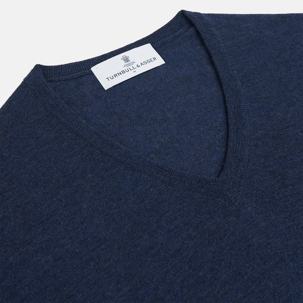 The Blue V-Neck Merino Wool Jumper by Turnbull & Asser features long sleeves, ribbed cuffs, and a ribbed hem—a timeless essential for any gentleman's wardrobe, shown laid flat on a white background.