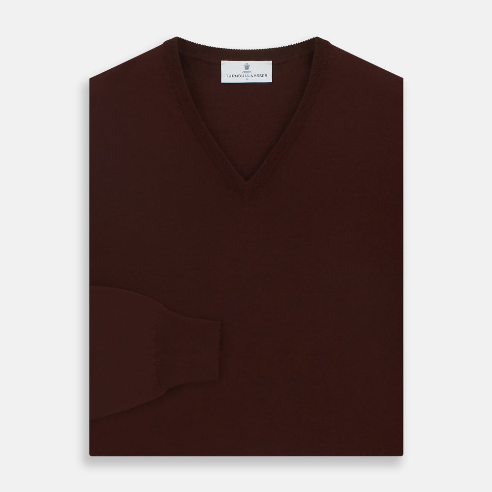 The Turnbull & Asser Wine V-Neck Merino Wool Jumper features long sleeves and ribbed cuffs and waistband, shown flat on a white background—a timeless staple for any gentleman’s wardrobe.