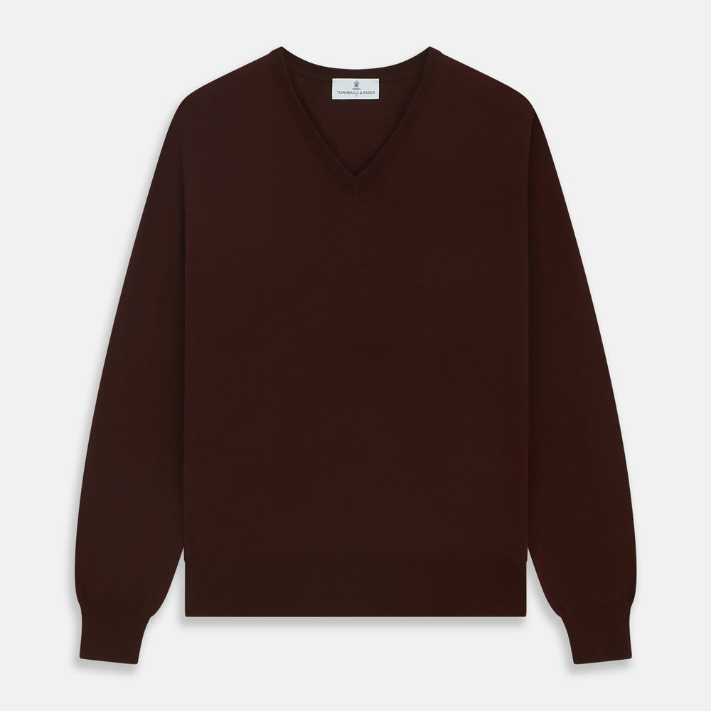 The Turnbull & Asser Wine V-Neck Merino Wool Jumper features long sleeves and ribbed cuffs and waistband, shown flat on a white background—a timeless staple for any gentleman’s wardrobe.