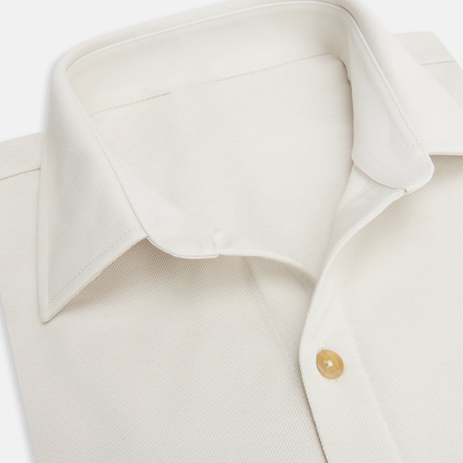 View 2 of product The Turnbull & Asser White Pique Shirt is a long-sleeve, white button-up with a chest pocket and beige buttons, laid flat on a white background, featuring an elevated silhouette inspired by elegant polos.