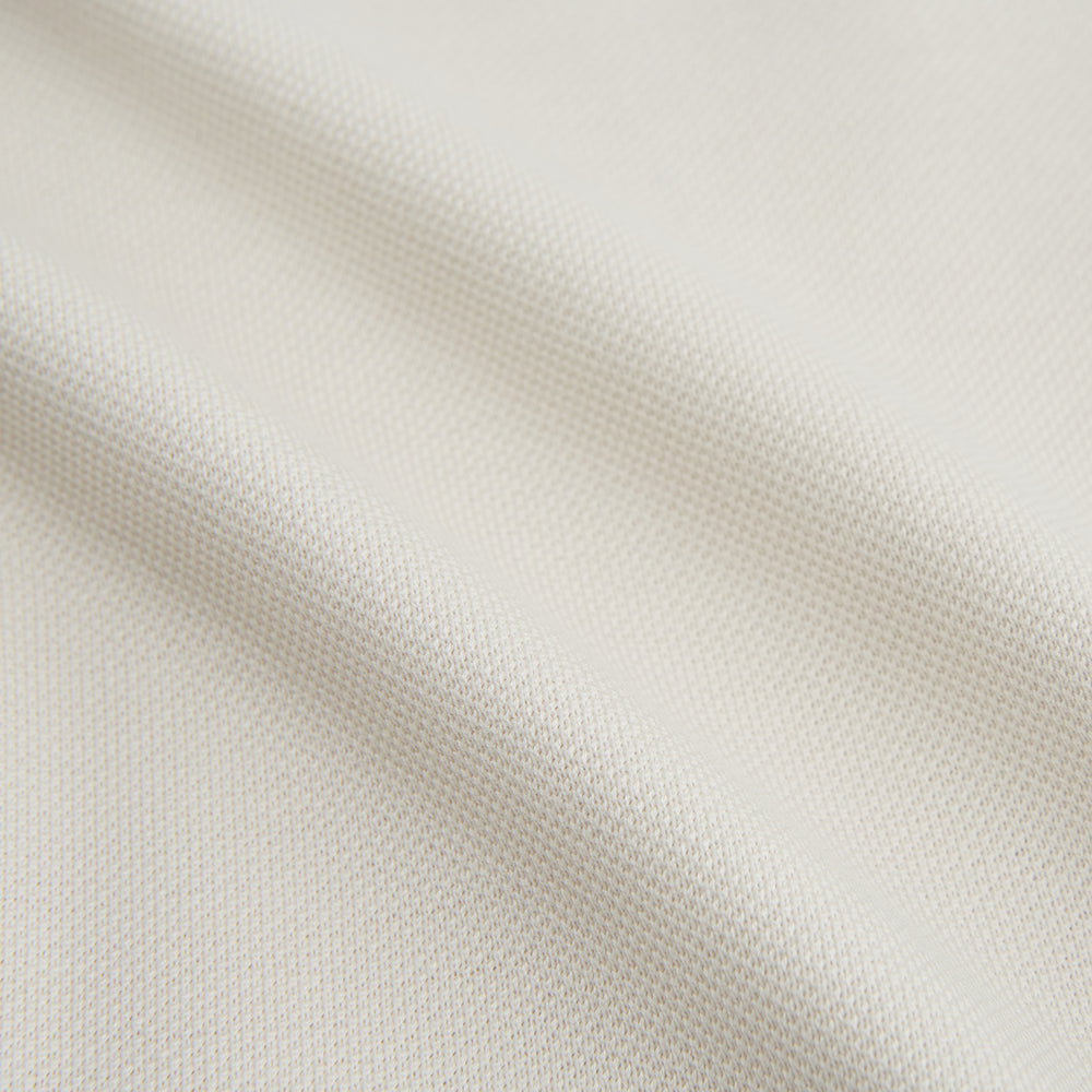 The Turnbull & Asser White Pique Shirt is a long-sleeve, white button-up with a chest pocket and beige buttons, laid flat on a white background, featuring an elevated silhouette inspired by elegant polos.