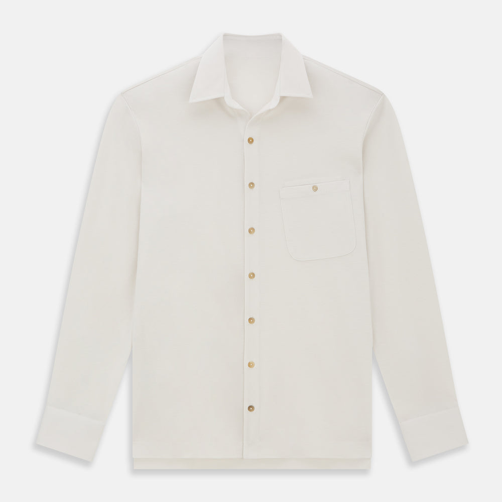 The Turnbull & Asser White Pique Shirt is a long-sleeve, white button-up with a chest pocket and beige buttons, laid flat on a white background, featuring an elevated silhouette inspired by elegant polos.