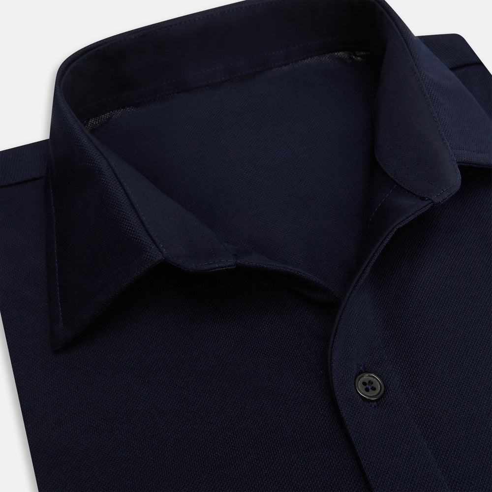 The Turnbull & Asser Navy Pique Shirt is a long-sleeved, dark navy button-up with a left chest pocket, classic collar, and buttoned cuffs, shown laid flat on a white background.