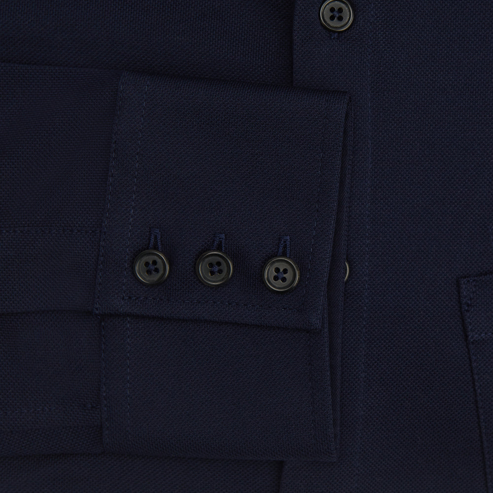 The Turnbull & Asser Navy Pique Shirt is a long-sleeved, dark navy button-up with a left chest pocket, classic collar, and buttoned cuffs, shown laid flat on a white background.