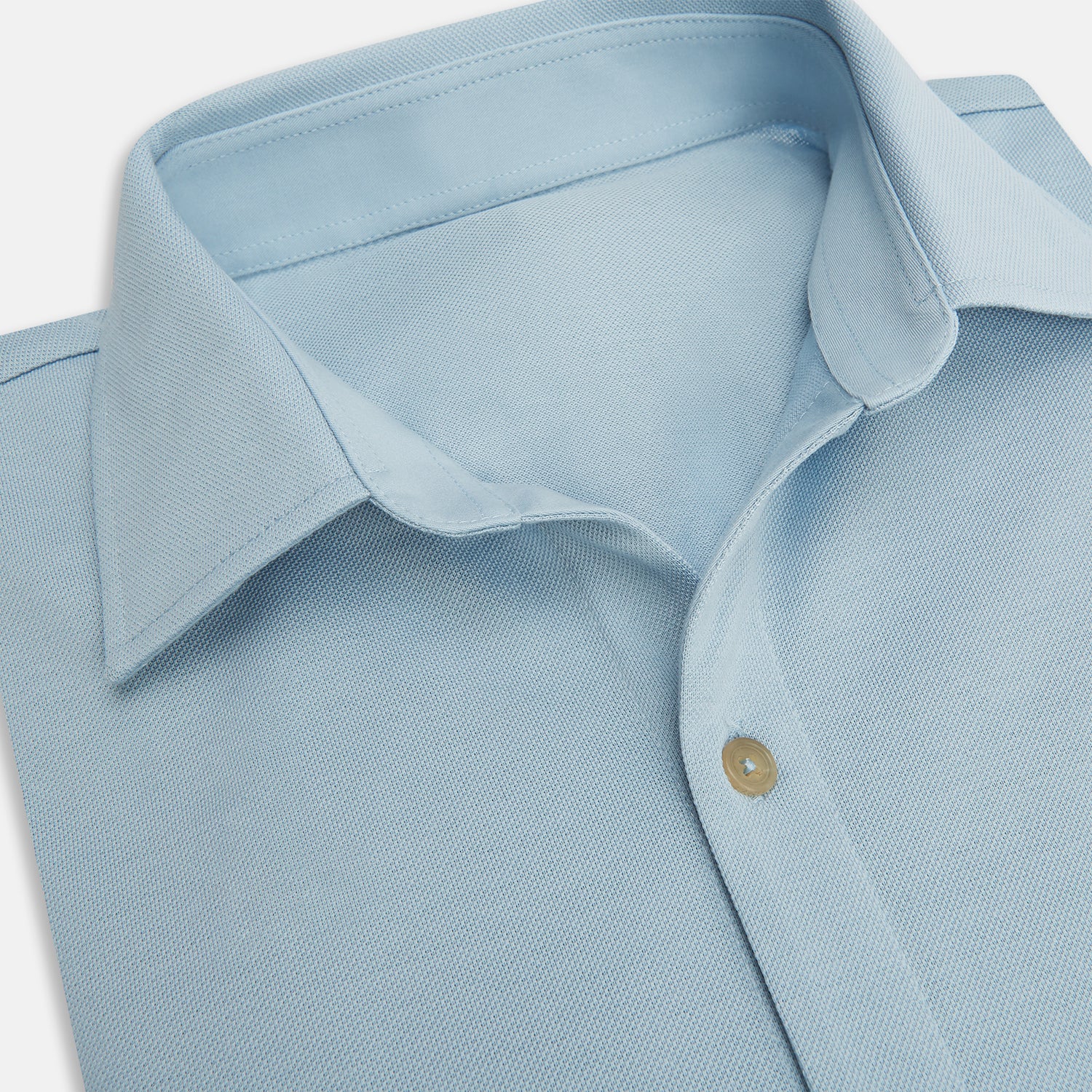 View 2 of product The Turnbull & Asser Pale Blue Pique Shirt is a long-sleeve button-up with an open collar, single chest pocket, and beige buttons, shown against a white background.