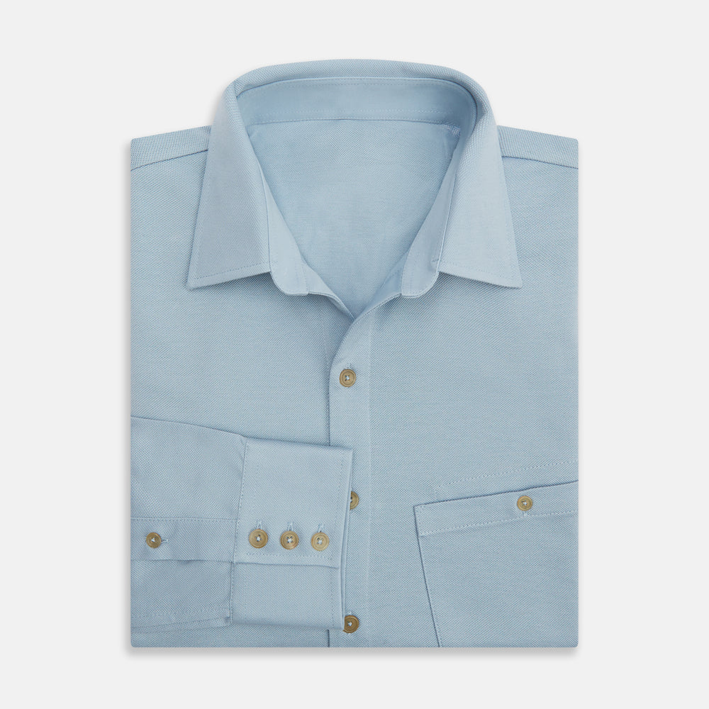 The Turnbull & Asser Pale Blue Pique Shirt is a long-sleeve button-up with an open collar, single chest pocket, and beige buttons, shown against a white background.