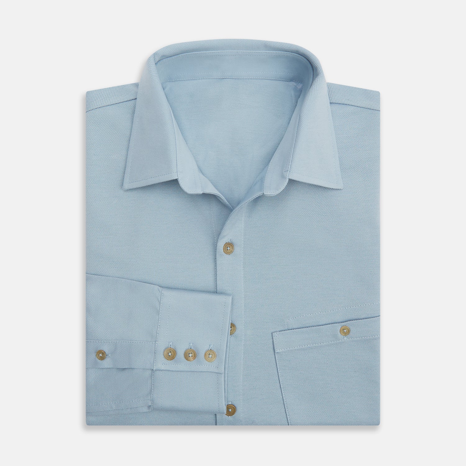 View 5 of product The Turnbull & Asser Pale Blue Pique Shirt is a long-sleeve button-up with an open collar, single chest pocket, and beige buttons, shown against a white background.