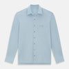 View 1 of product The Turnbull & Asser Pale Blue Pique Shirt is a long-sleeve button-up with an open collar, single chest pocket, and beige buttons, shown against a white background.