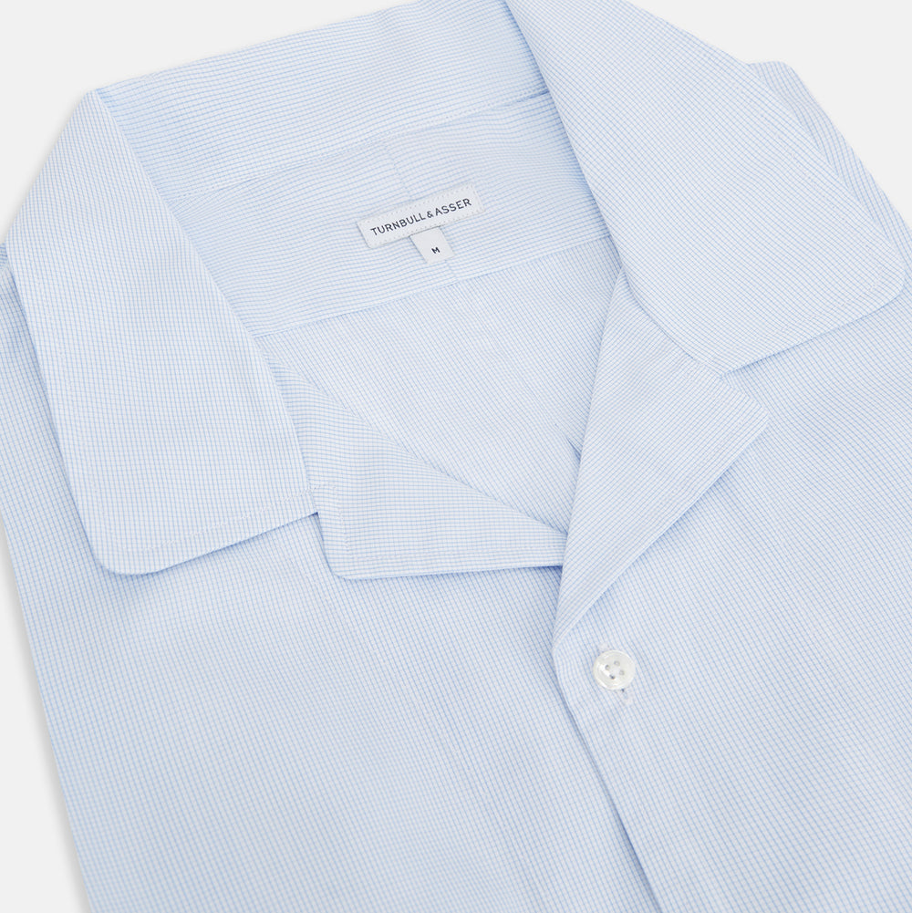 The Turnbull & Asser Pale Blue Fine Micro Check Nightshirt is a relaxed-fit, long-sleeve sleepwear piece with a collar, chest pocket, buttoned half-placket, and front pleat, shown against a plain white background.