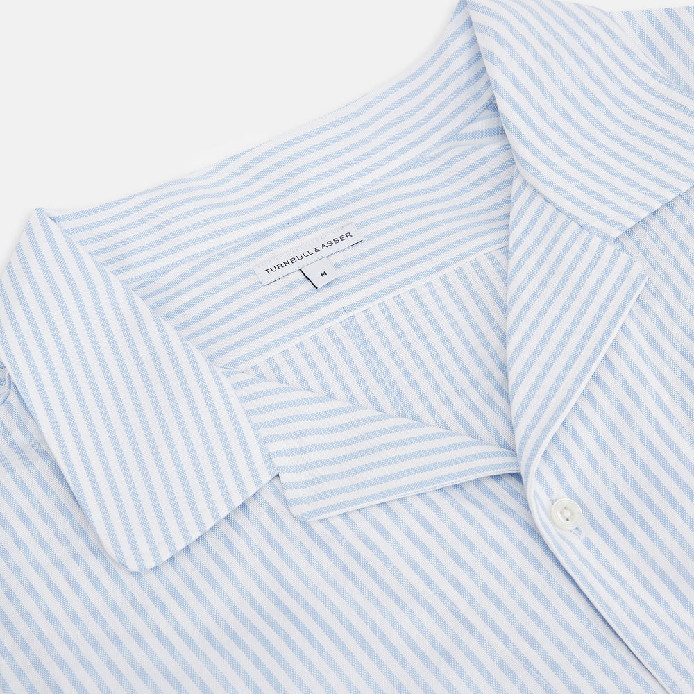 The Turnbull & Asser Pale Blue Bengal Stripe Nightshirt features light blue and white vertical stripes, a collar, chest pocket, and upper front buttons—perfect relaxing sleepwear, shown on a white background.