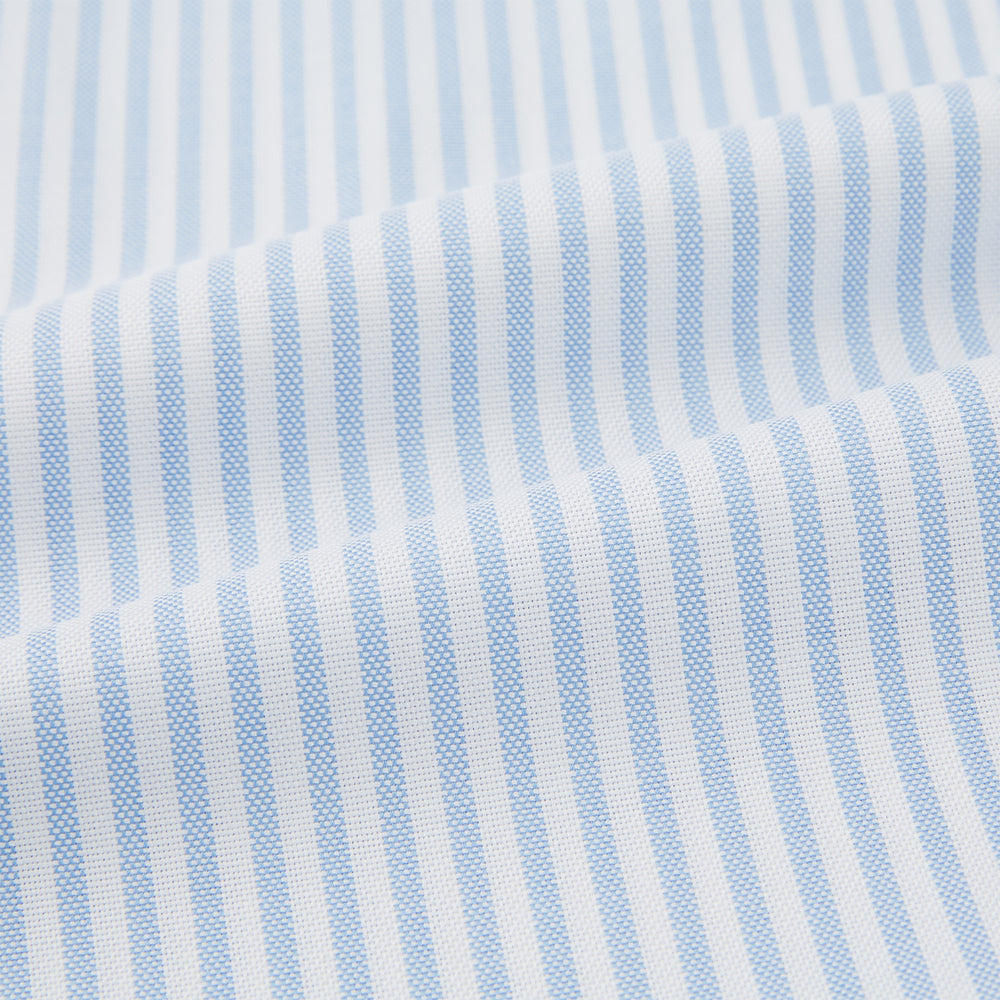 The Turnbull & Asser Pale Blue Bengal Stripe Nightshirt features light blue and white vertical stripes, a collar, chest pocket, and upper front buttons—perfect relaxing sleepwear, shown on a white background.