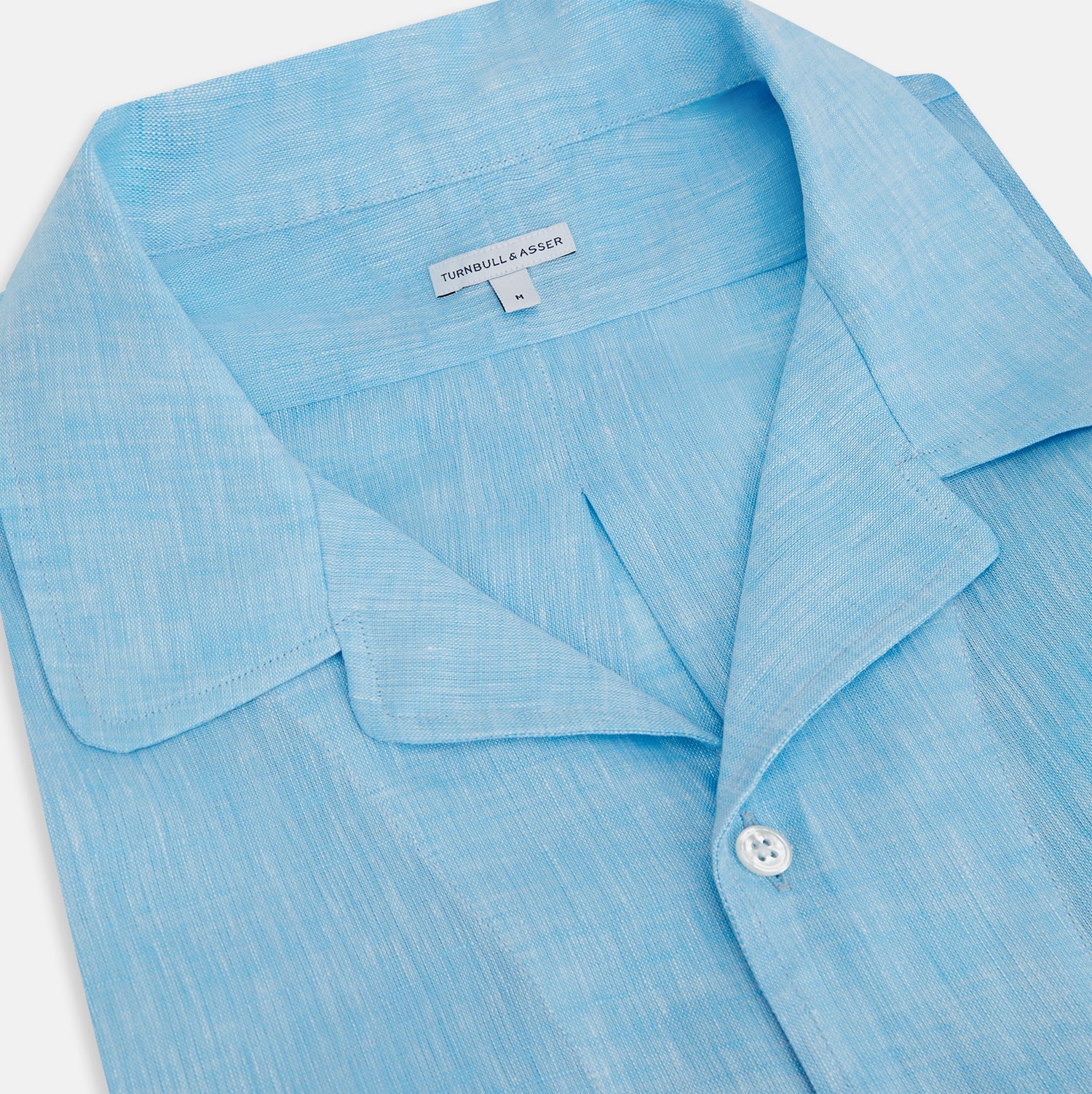 View 2 of product The Turnbull & Asser Turquoise Linen Nightshirt features long sleeves, a collar, button placket, single chest pocket, and a loose fit. Shown in light blue on a plain white background.