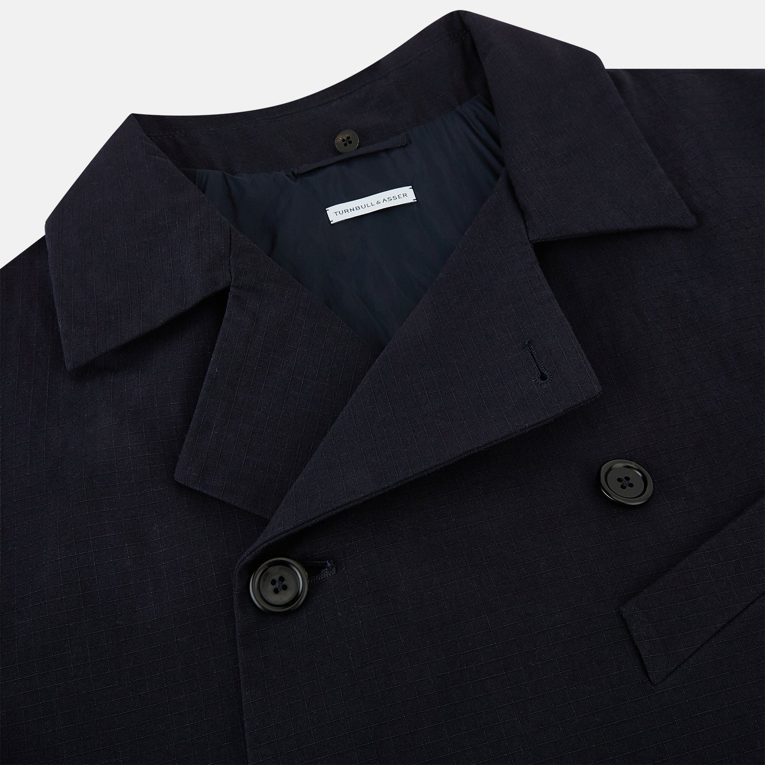 View 2 of product The Navy Short Albert Trench Coat by Turnbull & Asser UK features dark navy fabric, six black buttons, a notched collar, long sleeves with adjustable cuffs, and front zip pockets—displayed on a plain white background.
