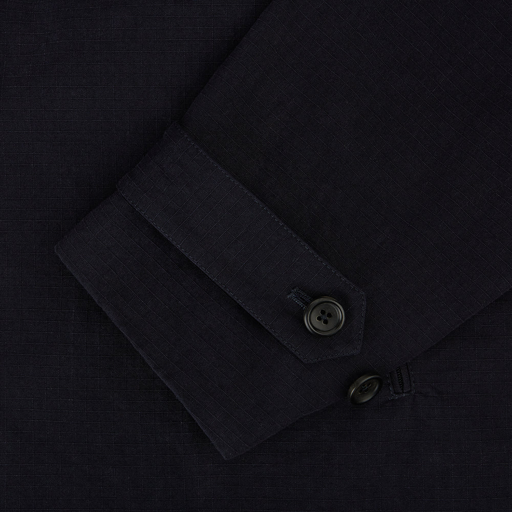 The Navy Short Albert Trench Coat by Turnbull & Asser UK features dark navy fabric, six black buttons, a notched collar, long sleeves with adjustable cuffs, and front zip pockets—displayed on a plain white background.