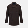View 1 of product The Turnbull & Asser UK Dark Chocolate Short Albert Trench Coat features a double-breasted style, black buttons, notched collar, chest pocket, two side zip pockets, and adjustable cuff straps—shown on a plain white background.