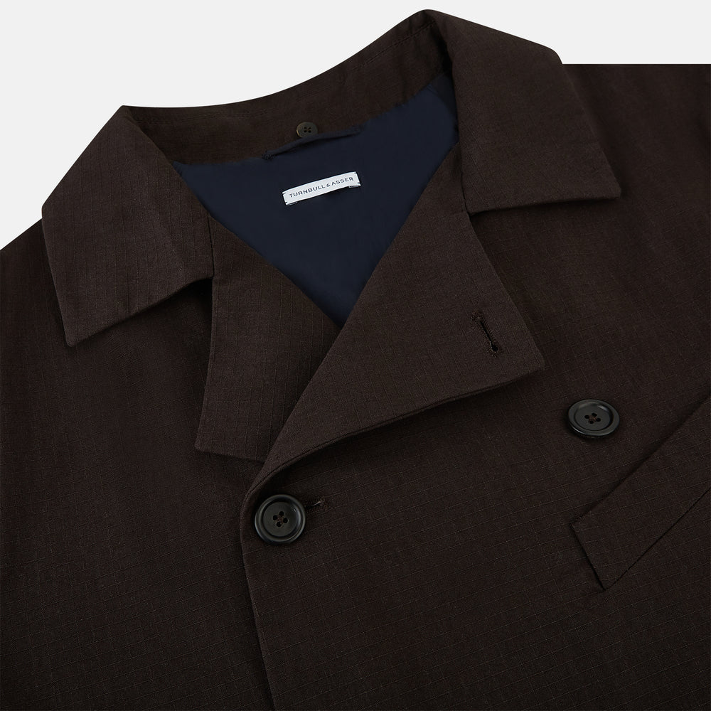 The Turnbull & Asser UK Dark Chocolate Short Albert Trench Coat features a double-breasted style, black buttons, notched collar, chest pocket, two side zip pockets, and adjustable cuff straps—shown on a plain white background.