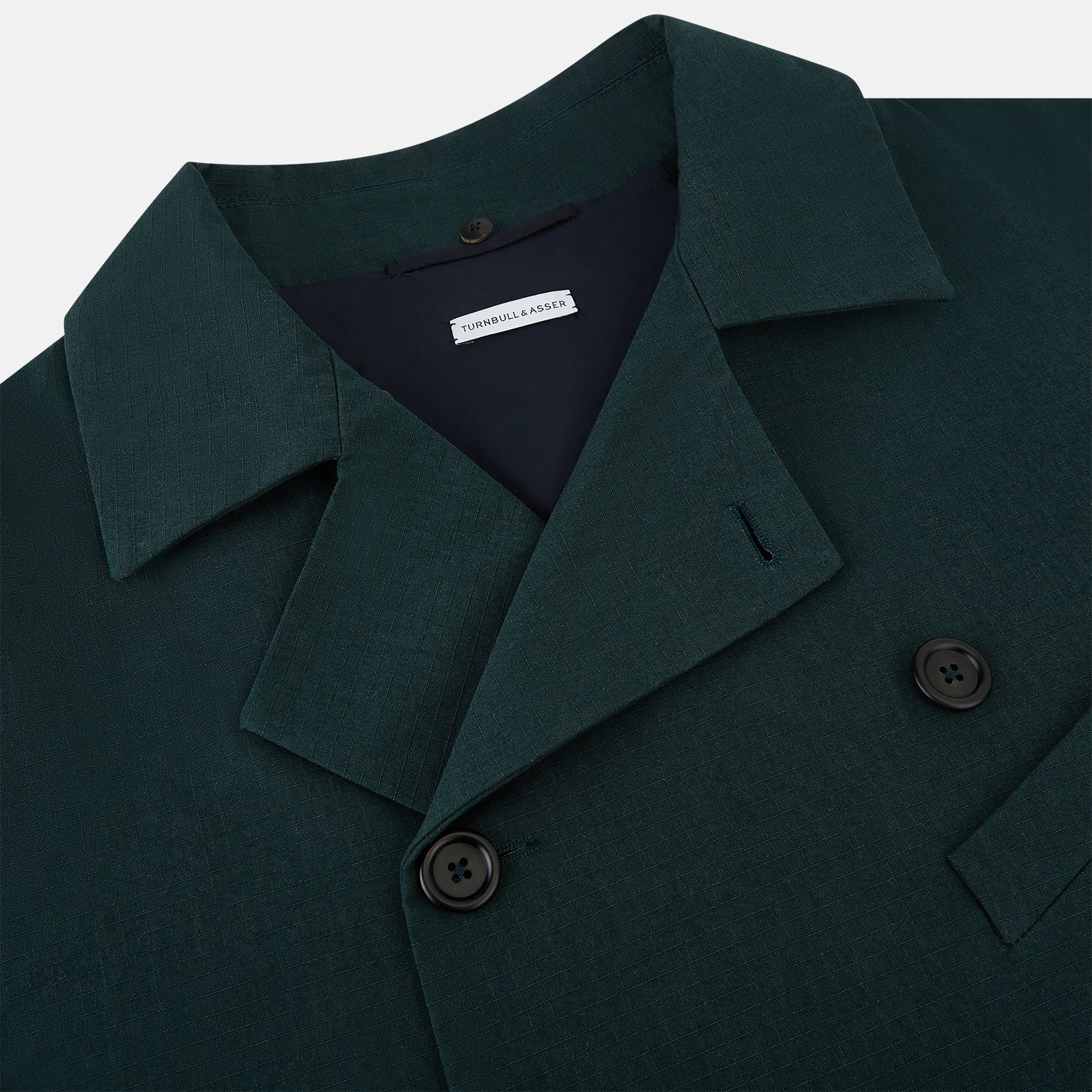 View 2 of product Turnbull & Asser UK's Forest Green Short Albert Trench Coat features a double-breasted design, black buttons, front chest pocket, two zippered side pockets, and strapped cuffs, shown against a plain white background.