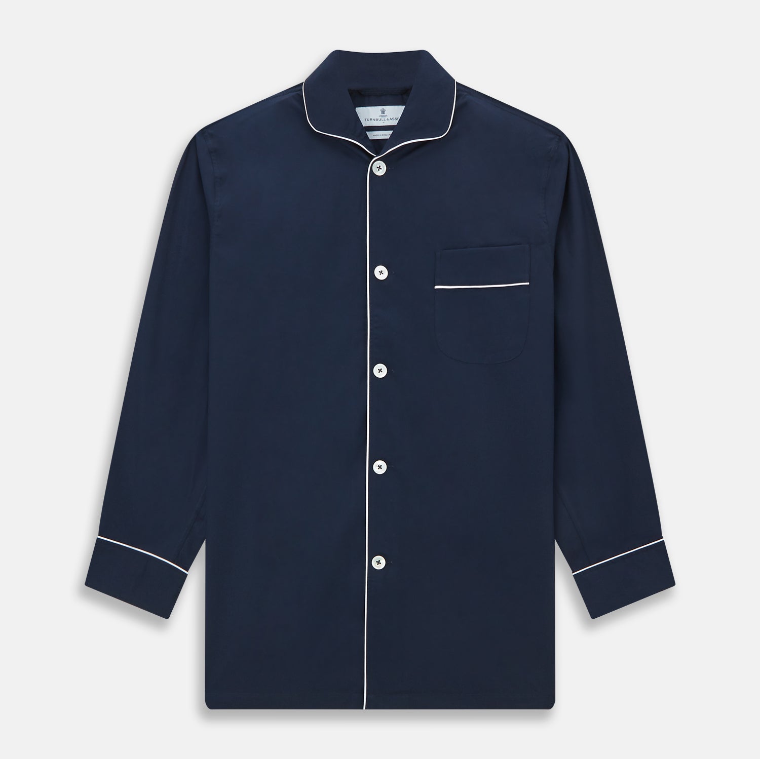 View 4 of product The Turnbull & Asser Navy Piped Cotton Pyjama Set features a navy blue long-sleeve top with white piping, front buttons, a chest pocket, and matching drawstring pants, all displayed on a white background.