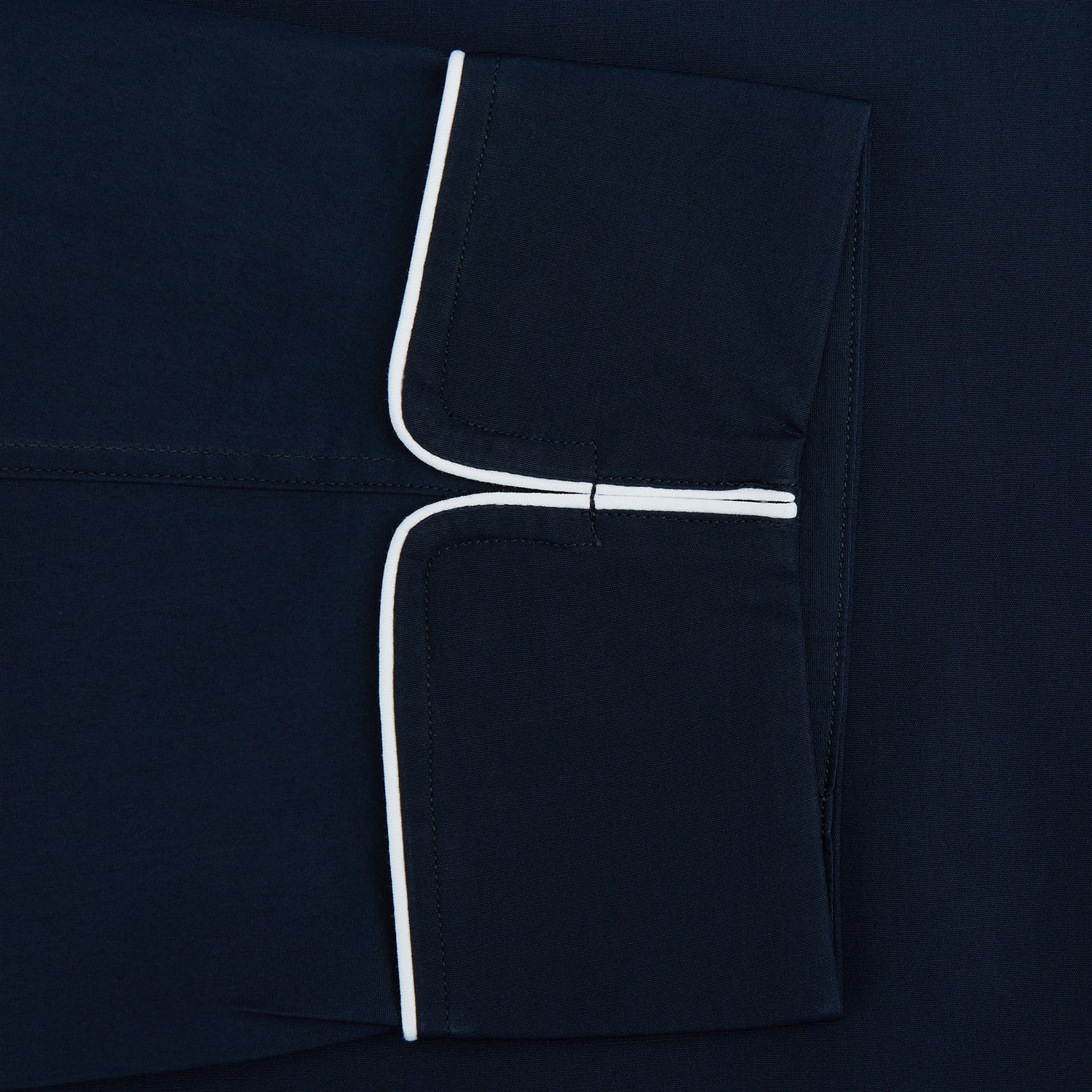 View 3 of product The Turnbull & Asser Navy Piped Cotton Pyjama Set features a navy blue long-sleeve top with white piping, front buttons, a chest pocket, and matching drawstring pants, all displayed on a white background.