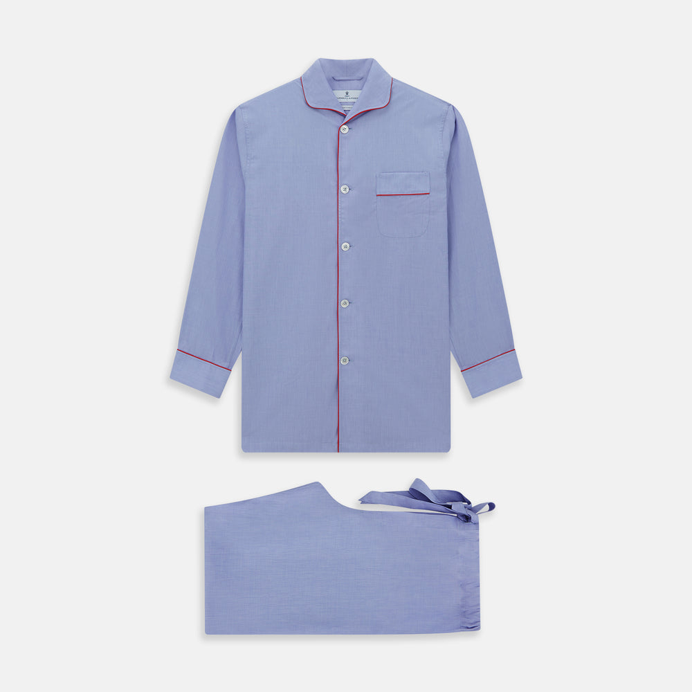 The Blue Piped End-on-End Cotton Pyjama Set by Turnbull & Asser features light blue long sleeves, red piping, front buttons, chest pocket, and matching drawstring pants—luxurious sleepwear laid flat on a white background.