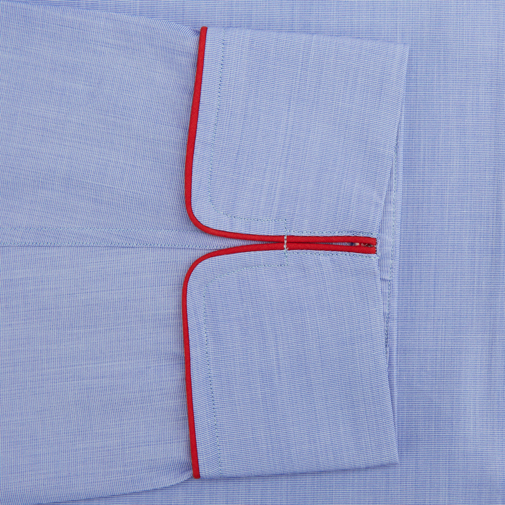 The Blue Piped End-on-End Cotton Pyjama Set by Turnbull & Asser features light blue long sleeves, red piping, front buttons, chest pocket, and matching drawstring pants—luxurious sleepwear laid flat on a white background.