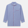 View 4 of product The Blue Piped End-on-End Cotton Pyjama Set by Turnbull & Asser features light blue long sleeves, red piping, front buttons, chest pocket, and matching drawstring pants—luxurious sleepwear laid flat on a white background.
