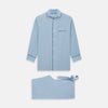 View 1 of product The Blue Piped Cotton-Cashmere Pyjama Set by Turnbull & Asser features a light blue long-sleeved, button-up top with a chest pocket and dark piping, plus matching side-tie pants—luxurious comfort displayed on a white background.