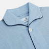 View 2 of product The Blue Piped Cotton-Cashmere Pyjama Set by Turnbull & Asser features a light blue long-sleeved, button-up top with a chest pocket and dark piping, plus matching side-tie pants—luxurious comfort displayed on a white background.