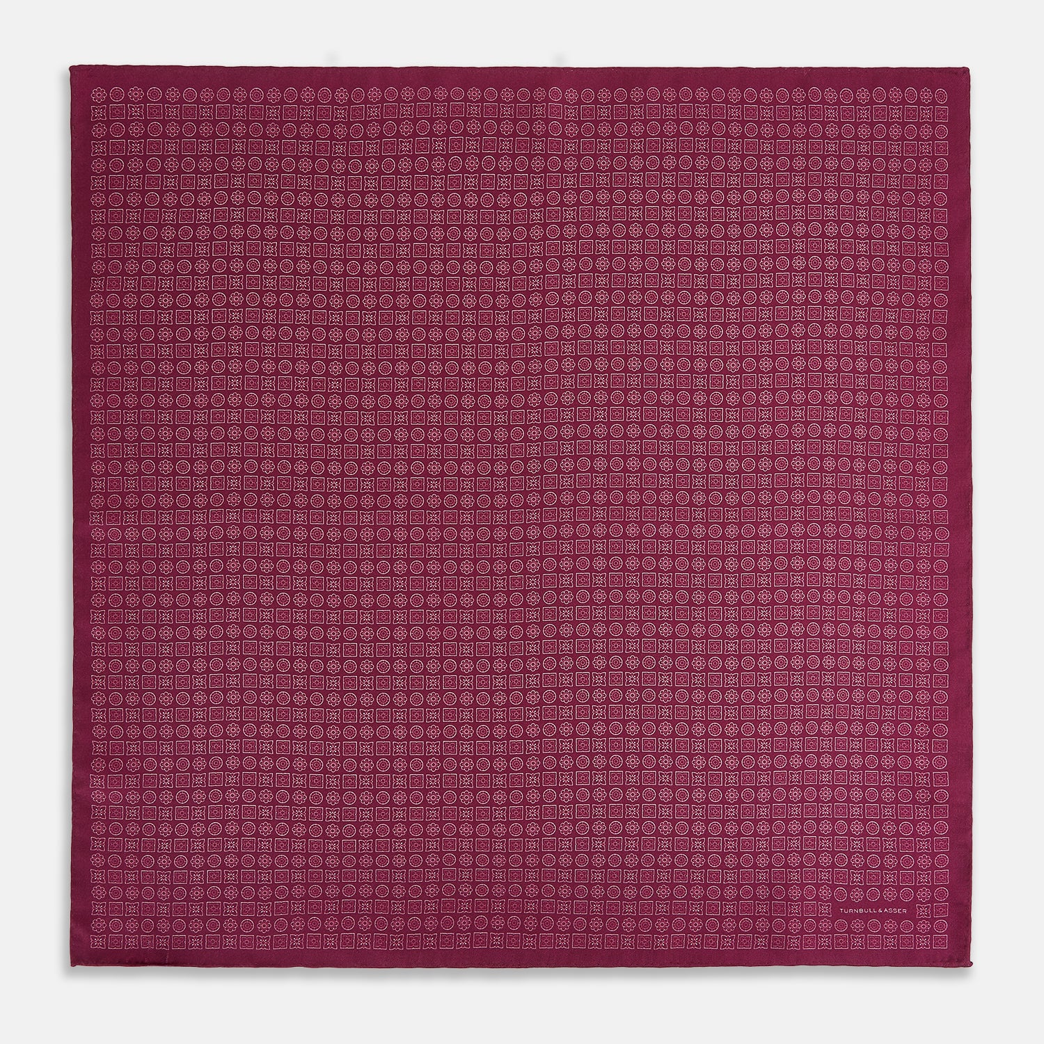 View 4 of product A folded Floral Burgundy Pocket Square in Silk by Turnbull & Asser UK, adorned with pink floral geometric motifs and featuring the Turnbull & Asser logo in the bottom right corner.