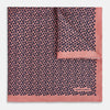 View 1 of product A folded Floral Pink Pocket Square in Silk by Turnbull & Asser UK, adorned with a pattern of small navy blue circles and the brand name printed in one corner, features a refined double-sided design for added versatility.