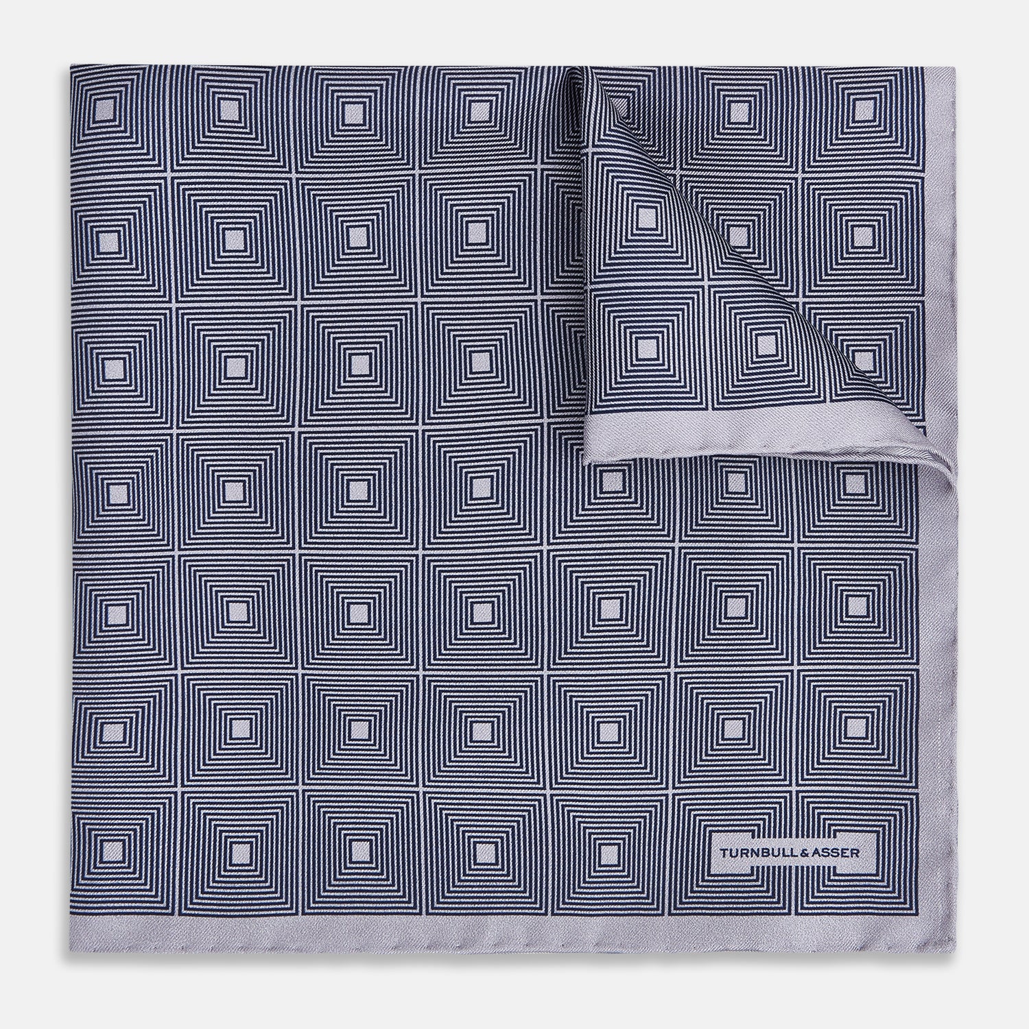 View 1 of product A folded, square Turnbull & Asser UK Geometric Grey Pocket Square in Silk featuring a geometric black and white concentric squares pattern accented with subtle navy lines, finished with a small Turnbull & Asser label in one corner.
