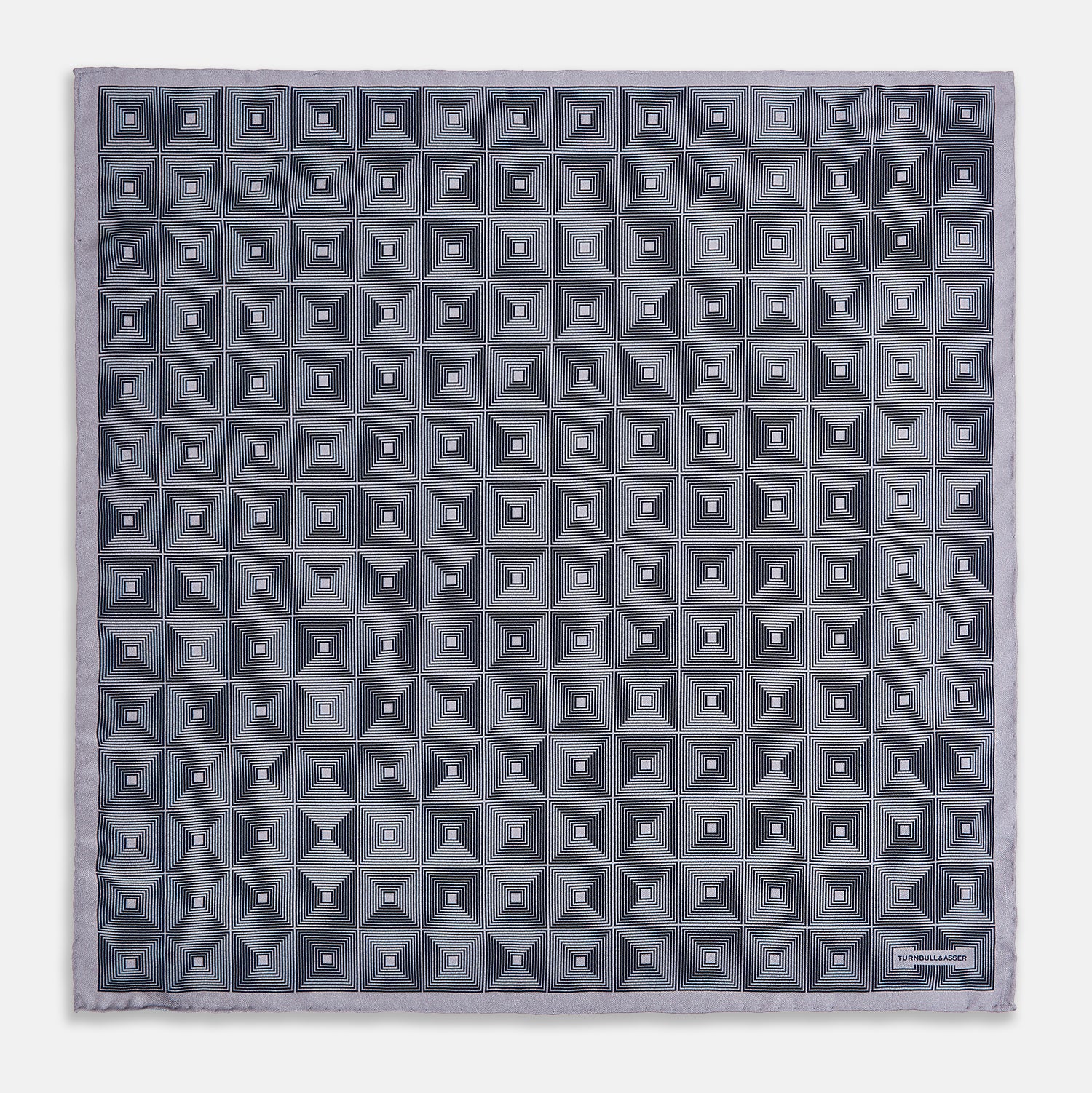 View 4 of product A folded, square Turnbull & Asser UK Geometric Grey Pocket Square in Silk featuring a geometric black and white concentric squares pattern accented with subtle navy lines, finished with a small Turnbull & Asser label in one corner.