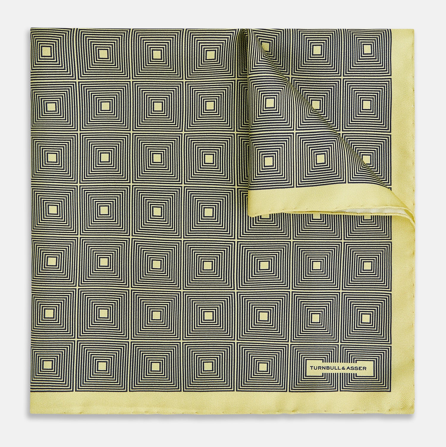 View 1 of product A checked yellow silk pocket square from Turnbull & Asser UK, featuring black and white concentric square designs with a yellow border. It is partially folded to highlight its double-sided pattern, and a small label reading TURNBULL & ASSER is visible in one corner.