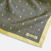 View 2 of product A checked yellow silk pocket square from Turnbull & Asser UK, featuring black and white concentric square designs with a yellow border. It is partially folded to highlight its double-sided pattern, and a small label reading TURNBULL & ASSER is visible in one corner.
