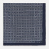 View 3 of product A Geometric Navy Pocket Square in Silk by Turnbull & Asser UK, showcasing a geometric pattern of small, overlapping concentric white squares and a stitched border. The pocket square is pictured with one corner folded over to display the Turnbull & Asser UK brand label.