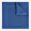 View 1 of product The Geometric Blue Pocket Square in Silk by Turnbull & Asser UK features a vibrant blue design adorned with small, outlined squares arranged in a grid of sharp navy lines. One corner is neatly folded to reveal the reverse side, with "Turnbull & Asser" printed at the bottom right.
