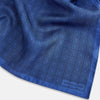 View 2 of product The Geometric Blue Pocket Square in Silk by Turnbull & Asser UK features a vibrant blue design adorned with small, outlined squares arranged in a grid of sharp navy lines. One corner is neatly folded to reveal the reverse side, with "Turnbull & Asser" printed at the bottom right.