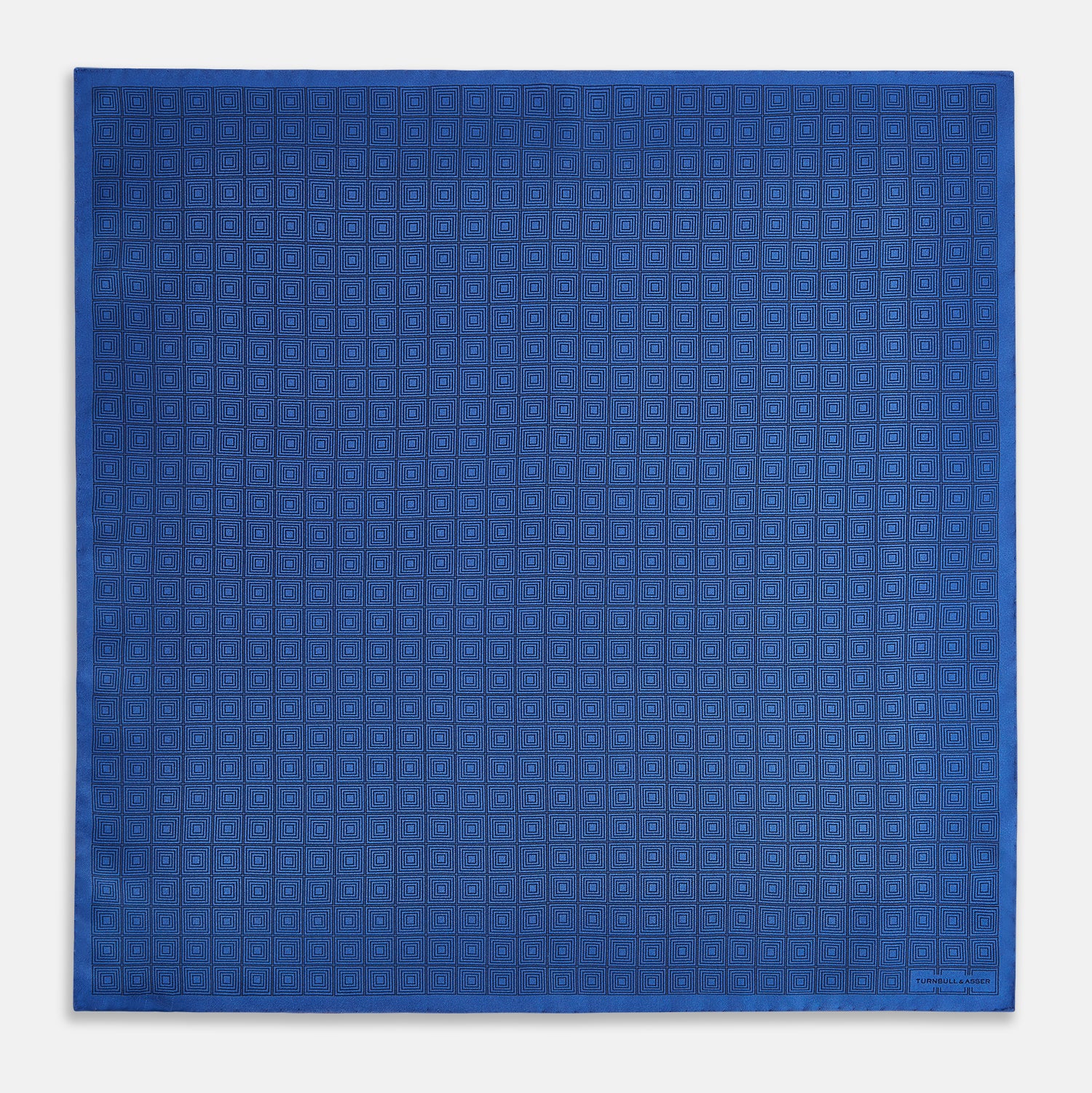 View 4 of product The Geometric Blue Pocket Square in Silk by Turnbull & Asser UK features a vibrant blue design adorned with small, outlined squares arranged in a grid of sharp navy lines. One corner is neatly folded to reveal the reverse side, with "Turnbull & Asser" printed at the bottom right.