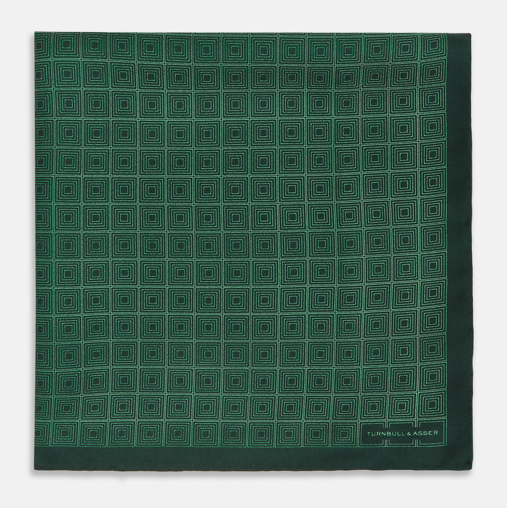 The Geometric Green Pocket Square in Silk by Turnbull & Asser UK features a sophisticated forest green hue with a geometric pattern of concentric squares and a visible Turnbull & Asser label in the corner.