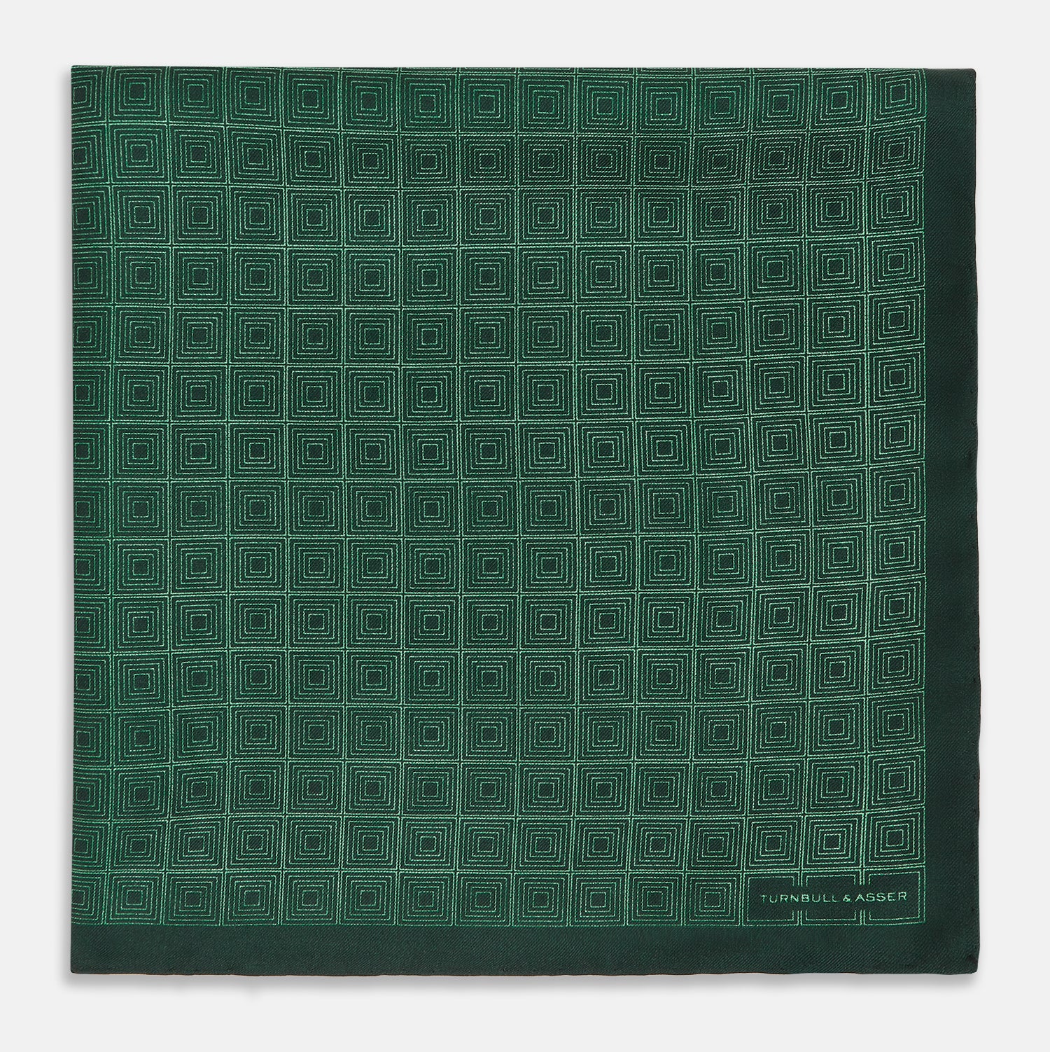 View 3 of product The Geometric Green Pocket Square in Silk by Turnbull & Asser UK features a sophisticated forest green hue with a geometric pattern of concentric squares and a visible Turnbull & Asser label in the corner.