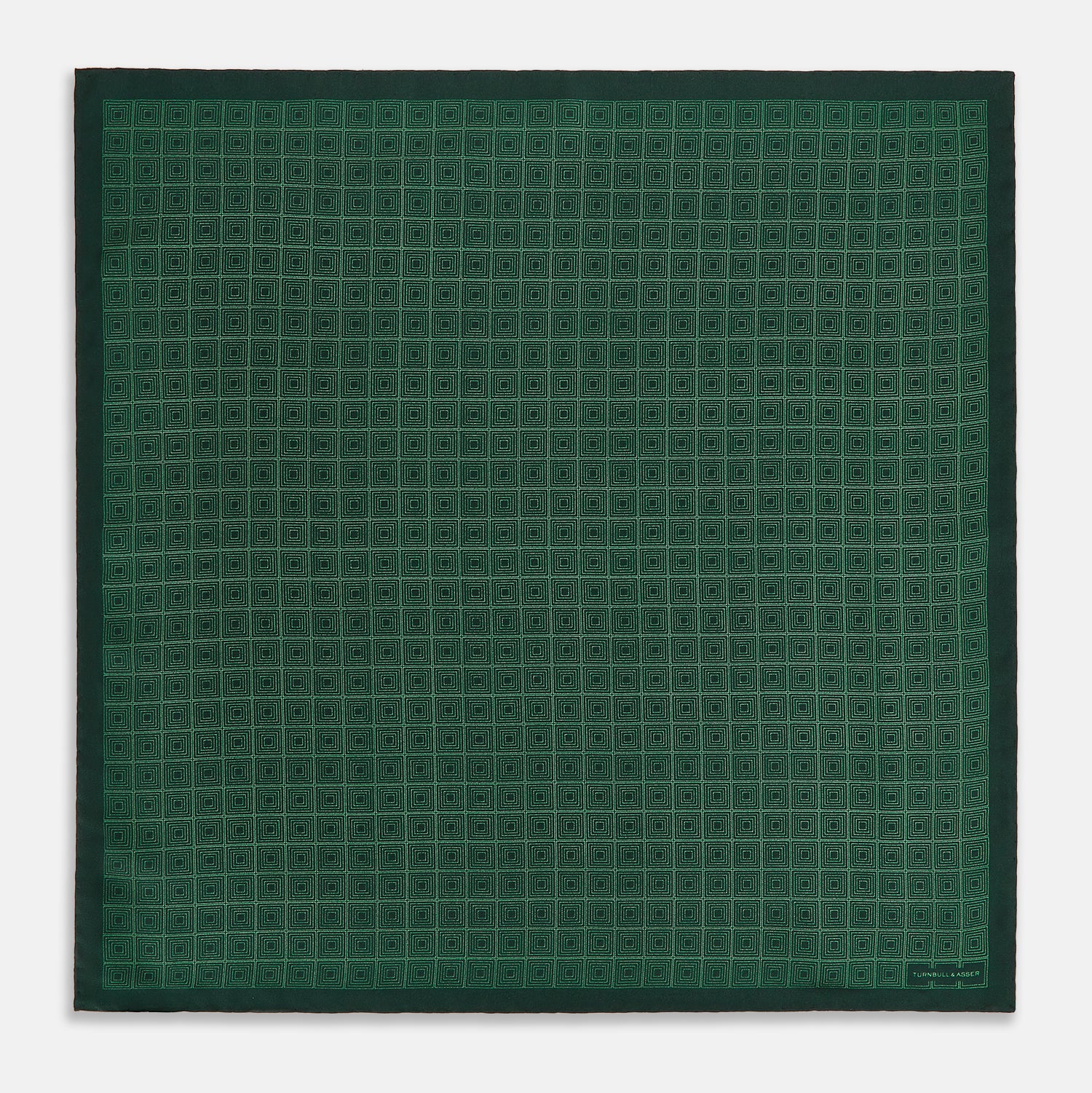 View 4 of product The Geometric Green Pocket Square in Silk by Turnbull & Asser UK features a sophisticated forest green hue with a geometric pattern of concentric squares and a visible Turnbull & Asser label in the corner.