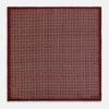 View 4 of product The Geometric Burgundy Pocket Square in Silk by Turnbull & Asser UK features a refined pattern of small, repeating white squares on a rich burgundy background—an ideal accessory for introducing sophistication to any outfit. One corner is artfully folded over to showcase the reverse side of this elegant geometric design, and the "Turnbull & Asser" label appears in the bottom right corner.
