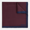 View 1 of product A Polka dot Burgundy Pocket Square in Silk by Turnbull & Asser UK, featuring a subtle micro motif and a solid navy border, partially folded at the top right corner.