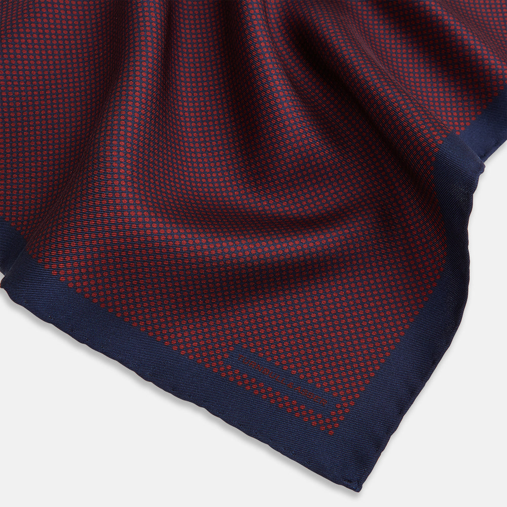 A Polka dot Burgundy Pocket Square in Silk by Turnbull & Asser UK, featuring a subtle micro motif and a solid navy border, partially folded at the top right corner.