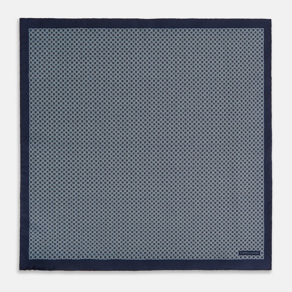 Introducing the Geometric Navy Pocket Square in Silk by Turnbull & Asser UK. This sophisticated accessory showcases a small, repeating geometric pattern in light blue and white on a rich navy background. The pocket square features a solid navy border, while the folded corner reveals the underside adorned with the Turnbull & Asser logo—an elegant finishing touch for any formal ensemble.