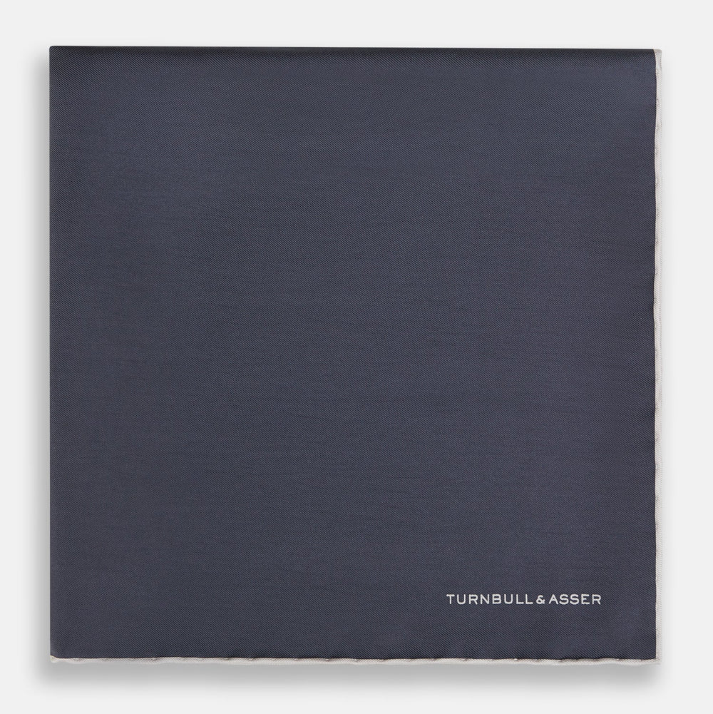 A neatly folded grey silk pocket square with ecru piping—ideal for formal wear—and TURNBULL & ASSER printed in white in one corner.